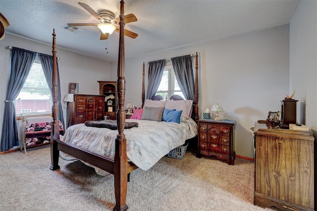 carpeted bedroom featuring a ceiling fan, visible vents, a textured ceiling, and baseboards