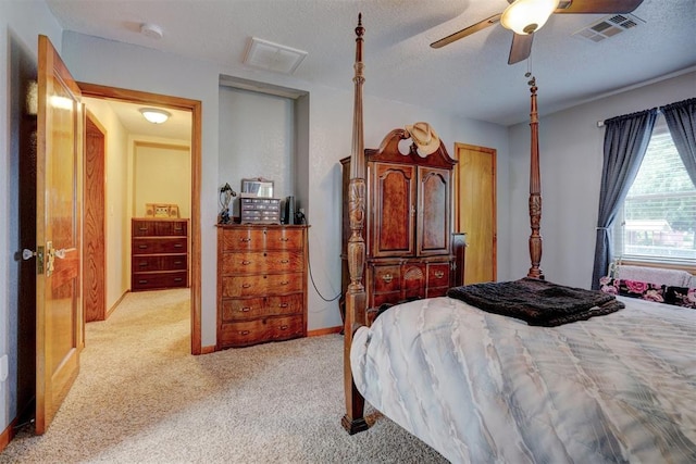 bedroom featuring a ceiling fan, light colored carpet, visible vents, and a textured ceiling