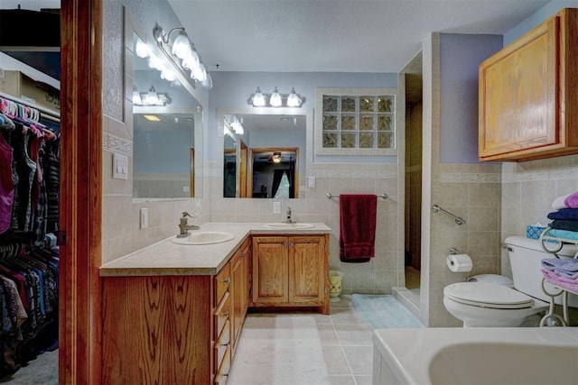 bathroom featuring tile patterned flooring, tile walls, a sink, and tiled shower