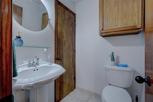 bathroom featuring toilet, baseboards, a sink, and tile patterned floors