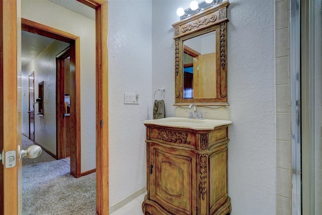 bathroom featuring a textured wall, baseboards, and vanity