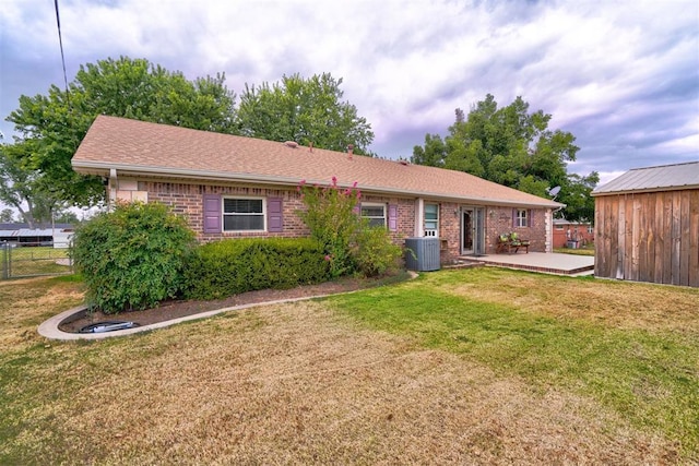 ranch-style house with brick siding, a patio, central AC unit, a front yard, and fence