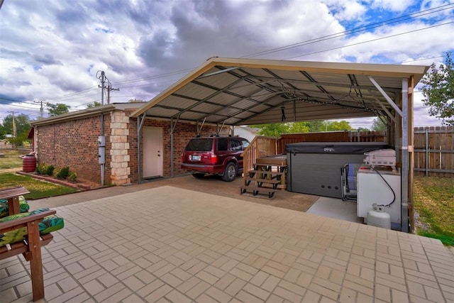 view of parking / parking lot featuring decorative driveway, fence, and a detached carport