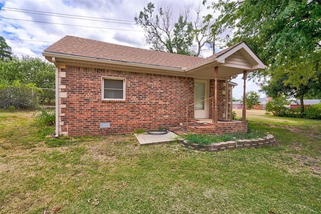 view of home's exterior featuring a yard, brick siding, and a shingled roof