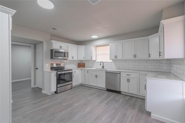 kitchen featuring stainless steel appliances, light countertops, visible vents, decorative backsplash, and a sink