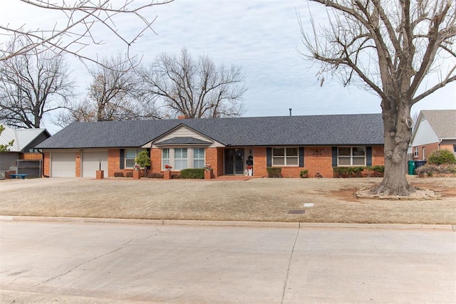 ranch-style home with a garage, brick siding, driveway, and a shingled roof