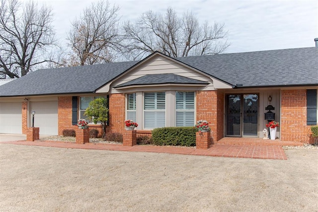 ranch-style house with an attached garage, driveway, brick siding, and a shingled roof