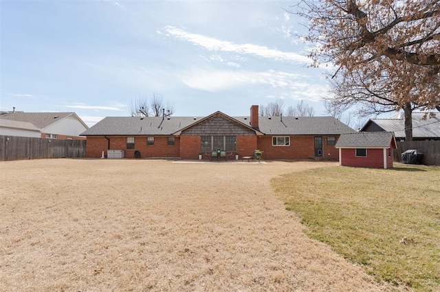 back of house featuring a patio, a chimney, fence, an outdoor structure, and a shed