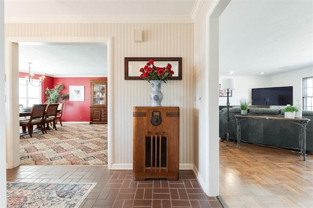 hall with a healthy amount of sunlight, crown molding, a notable chandelier, and baseboards