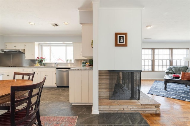 kitchen featuring light countertops, stainless steel dishwasher, plenty of natural light, and under cabinet range hood