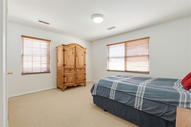 bedroom with light colored carpet, visible vents, and multiple windows