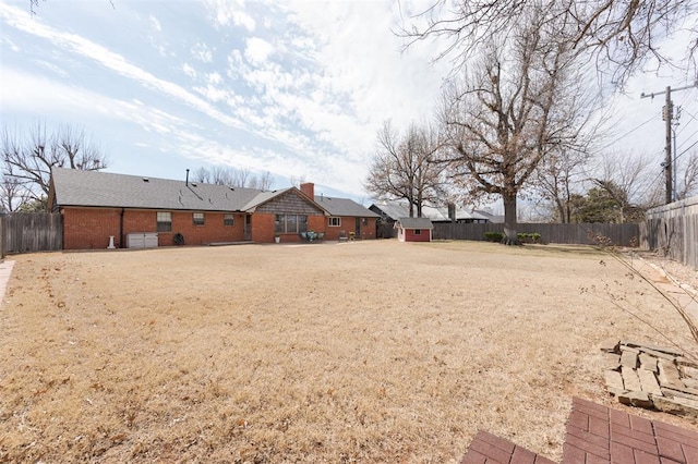 view of yard with a fenced backyard, a storage unit, and an outdoor structure