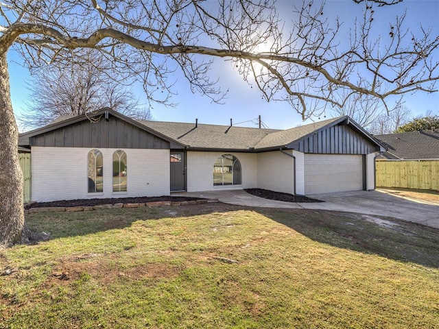 view of front facade featuring driveway, fence, a front lawn, and brick siding