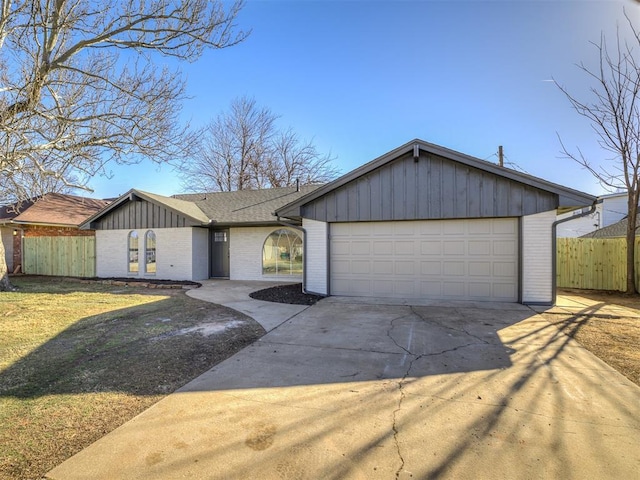 view of front of home featuring a garage, concrete driveway, fence, board and batten siding, and brick siding