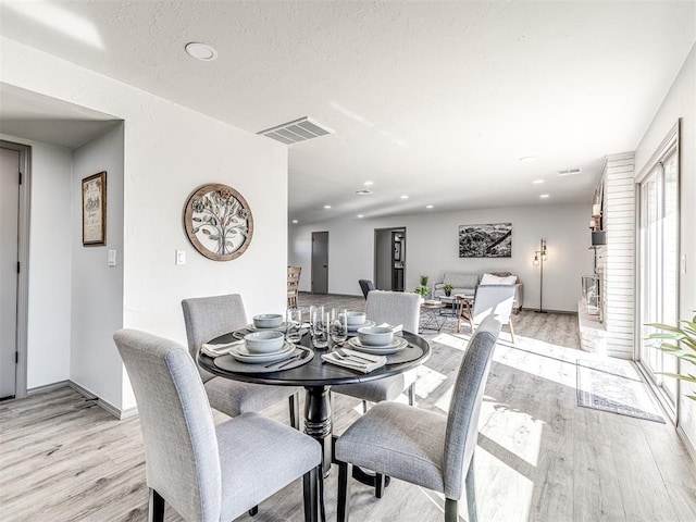 dining area featuring recessed lighting, visible vents, a textured ceiling, and light wood finished floors