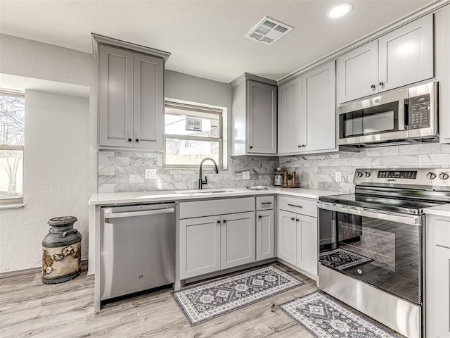 kitchen with visible vents, appliances with stainless steel finishes, gray cabinets, and a sink