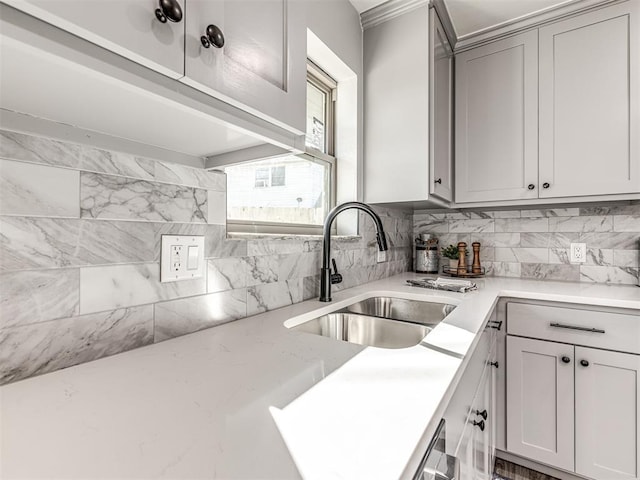 kitchen featuring tasteful backsplash, gray cabinets, a sink, and light stone countertops