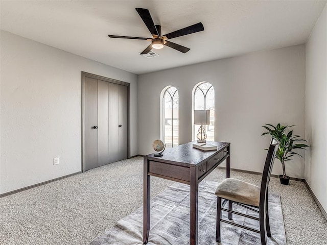 office area with light carpet, a ceiling fan, visible vents, and baseboards