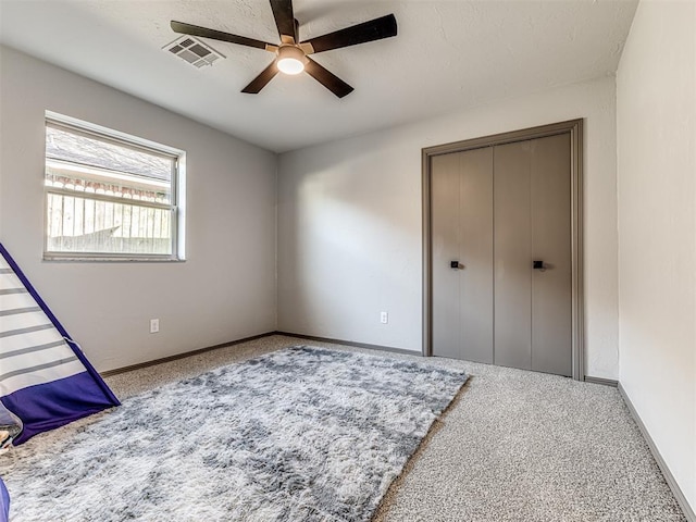 carpeted bedroom featuring a ceiling fan, a closet, visible vents, and baseboards