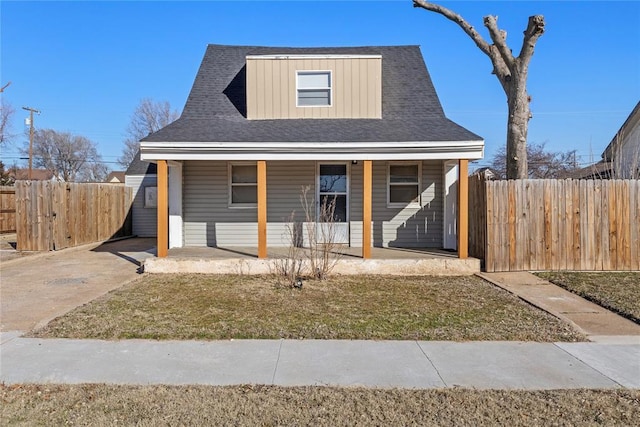 bungalow featuring a front lawn, fence, and a porch