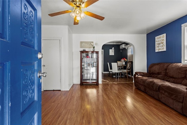 living room featuring ceiling fan, arched walkways, and dark wood-type flooring