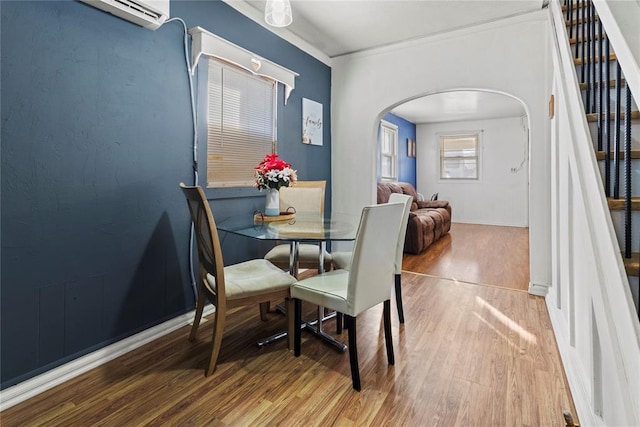 dining room featuring stairs, arched walkways, a wall mounted AC, and wood finished floors