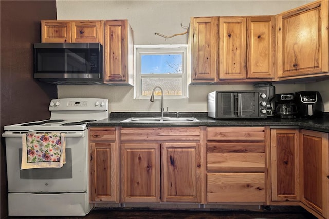 kitchen featuring electric range, a sink, brown cabinetry, stainless steel microwave, and dark countertops