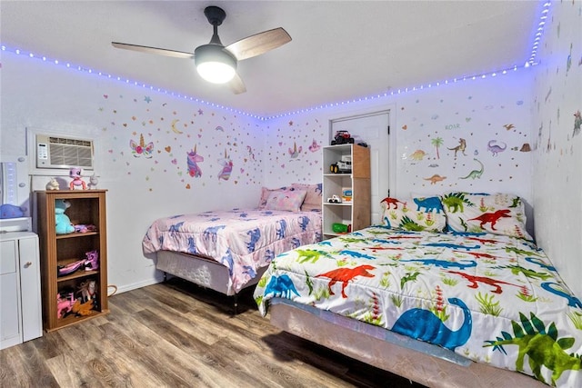 bedroom featuring an AC wall unit, wallpapered walls, ceiling fan, and wood finished floors