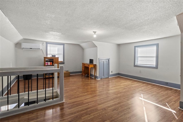 bonus room featuring dark wood-type flooring, vaulted ceiling, baseboards, and a wall mounted AC