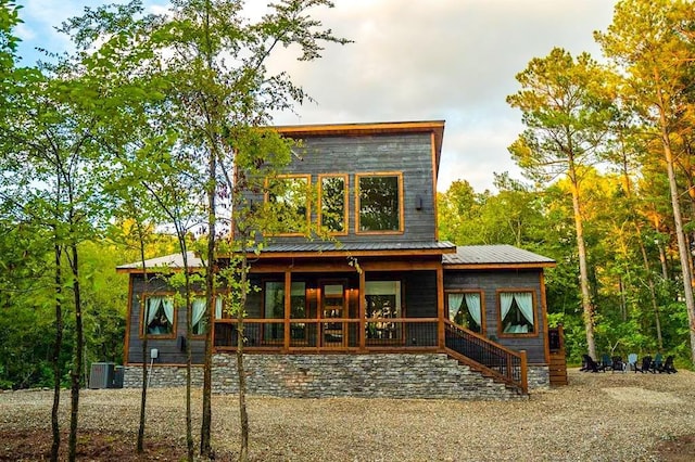 rear view of property featuring cooling unit, covered porch, and metal roof