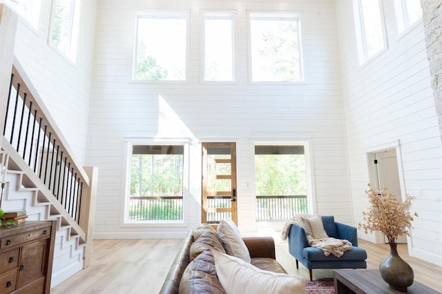 living area featuring light wood finished floors, a high ceiling, and stairway