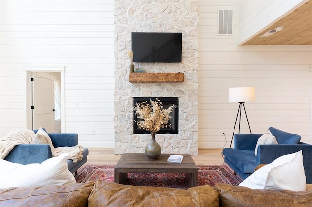 living room with wood walls, a fireplace, wood finished floors, and visible vents