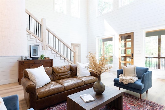 living room featuring a high ceiling, stairway, wood finished floors, and a wealth of natural light