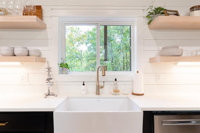 kitchen featuring stainless steel dishwasher, open shelves, a sink, and light countertops