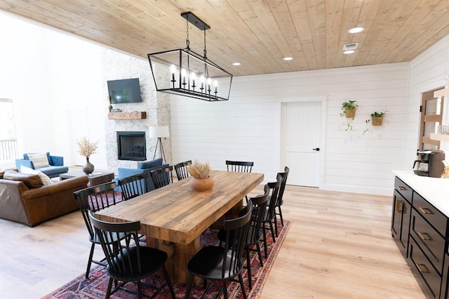 dining room featuring light wood-style floors, recessed lighting, wooden ceiling, and a fireplace