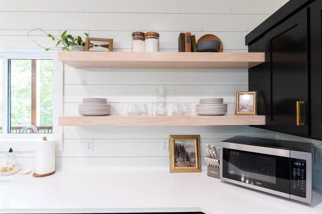 interior details featuring stainless steel microwave, open shelves, and light countertops