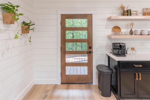 doorway featuring wooden walls and light wood finished floors