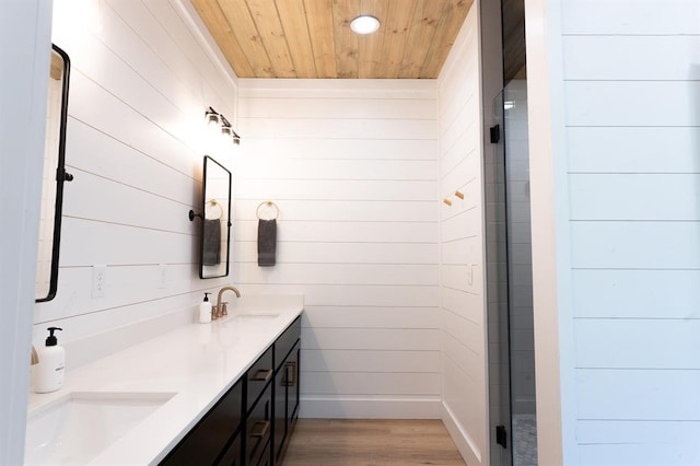 full bath with double vanity, wooden ceiling, a shower stall, and a sink