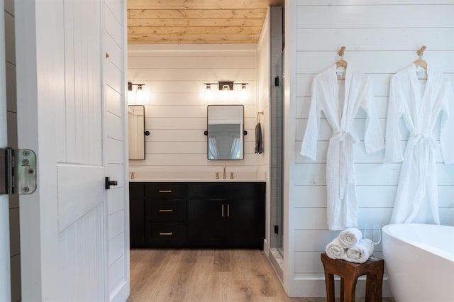 full bath with wood walls, wood finished floors, vanity, a soaking tub, and a shower stall