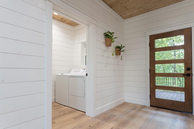 laundry area with wooden ceiling, washing machine and dryer, wooden walls, light wood-type flooring, and laundry area