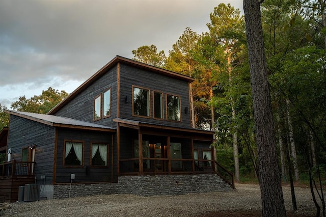 back of house featuring covered porch, metal roof, and cooling unit