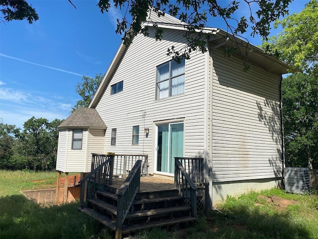 back of property with a deck and central AC