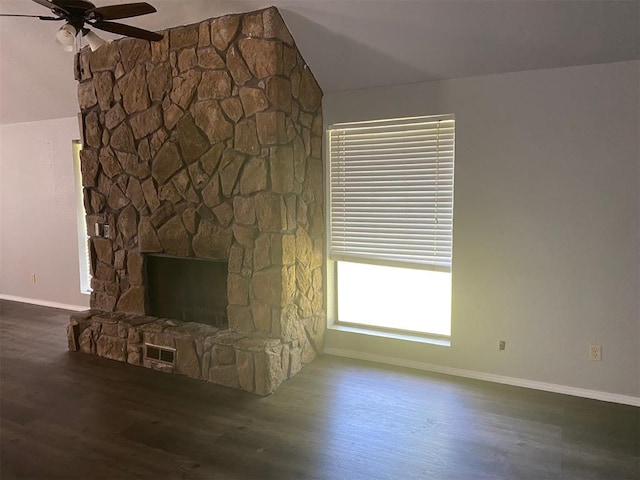 unfurnished living room with visible vents, ceiling fan, vaulted ceiling, a stone fireplace, and wood finished floors