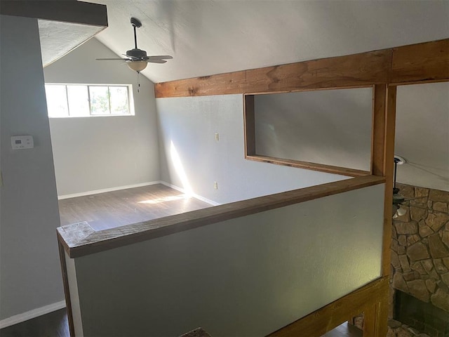 interior space featuring a ceiling fan, lofted ceiling, baseboards, and wood finished floors