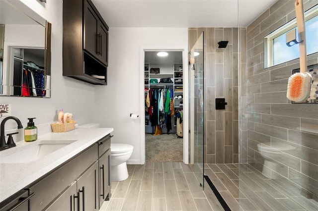 bathroom featuring toilet, a stall shower, a walk in closet, and vanity