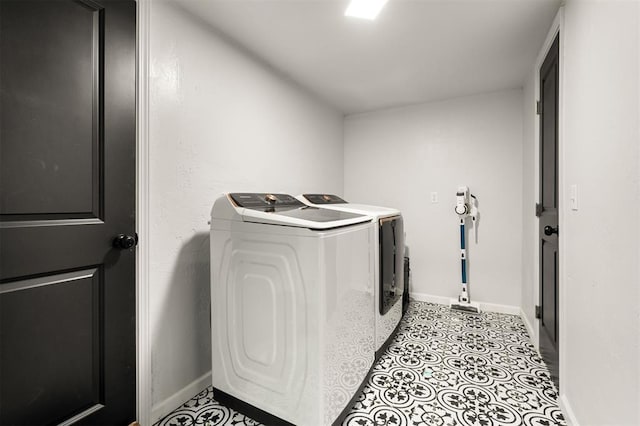 clothes washing area with laundry area, light tile patterned floors, baseboards, and separate washer and dryer