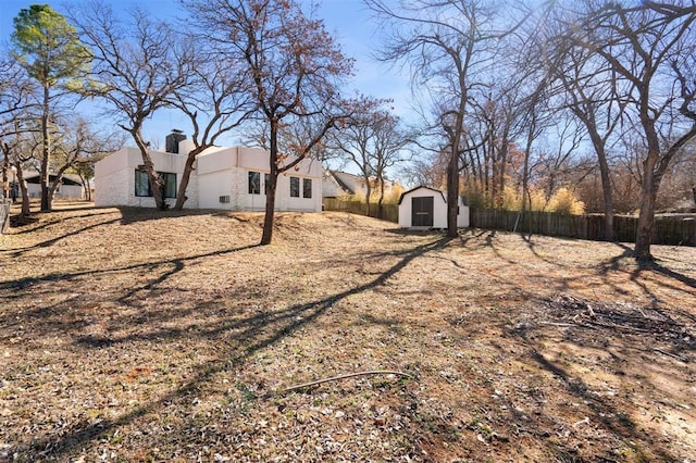 view of yard featuring an outdoor structure, fence, and a storage unit