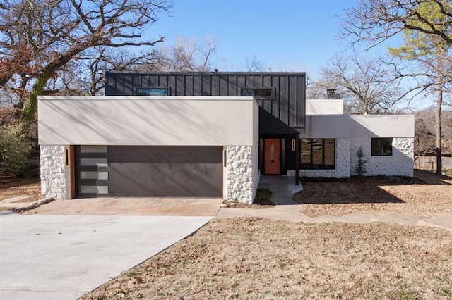 contemporary house featuring a garage, stone siding, driveway, and board and batten siding