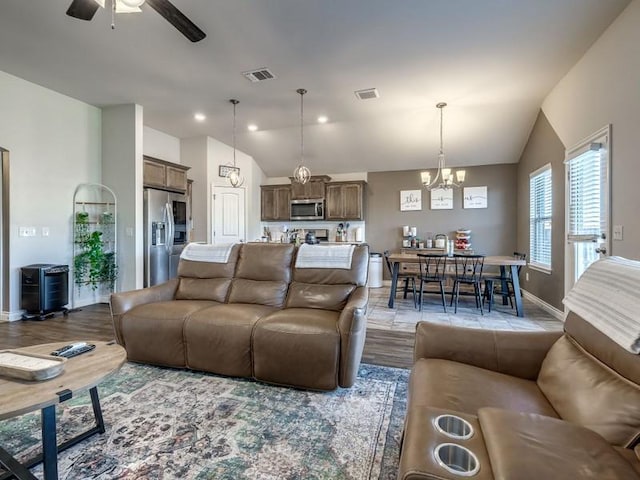 living area with lofted ceiling, visible vents, and wood finished floors