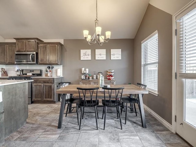 dining space featuring a chandelier, lofted ceiling, and baseboards